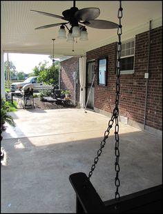 a porch with a ceiling fan and some lights hanging from it's side wall