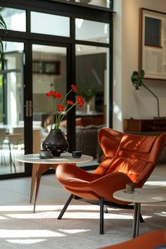 an orange chair sitting next to a table with flowers on it in front of a glass door