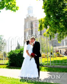 a bride and groom kissing in front of a building