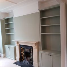 an empty living room with a fireplace and built - in bookcases on either side