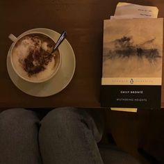 a cup of coffee sitting on top of a table next to a book