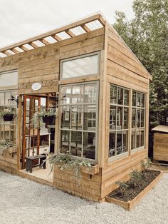 a small wooden building with lots of windows and plants in the window sills