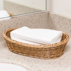 wicker basket with folded white napkins on countertop in bathroom area next to sink