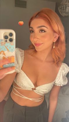 a woman taking a selfie with her cell phone and wearing a white bra top