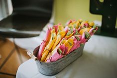 a basket filled with yellow and pink flowers sitting on top of a white table cloth