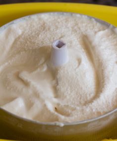 a yellow bowl filled with whipped cream on top of a table