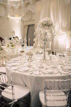 the table is set with white flowers and place settings for guests to sit down at