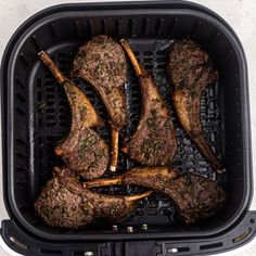 the meat is being cooked in an air fryer with tongs and seasoning