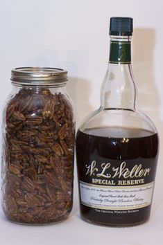 a bottle of liquor next to a jar filled with nuts