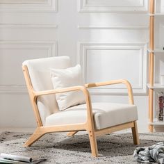 a white chair sitting on top of a rug next to a book shelf filled with books