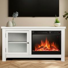 a white entertainment center with an electric fire in the fireplace and a television mounted above it