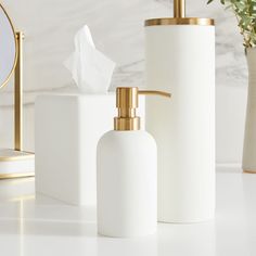 three white bathroom accessories including soap dispenser and tissue dispenser