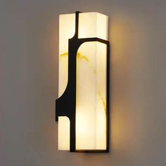 a wall light that is mounted to the side of a wall with a white and black design