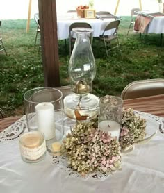 the table is set with candles, flowers and glass vases on top of it