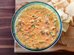 a bowl of salsa with tortilla chips on a cutting board next to it