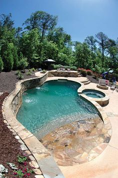 an outdoor swimming pool surrounded by landscaping and trees