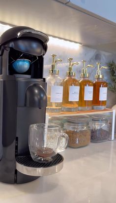 a coffee maker sitting on top of a counter next to cups and jars filled with liquid