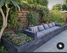 a couch sitting in the middle of a garden next to a wall with plants growing on it