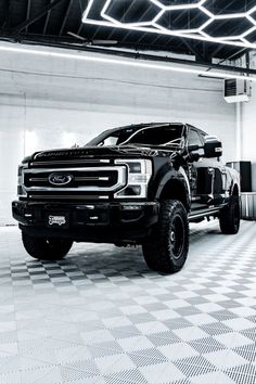 a black and white photo of a truck parked in a garage with checkered flooring