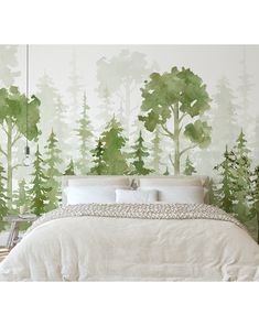 a bed sitting in front of a wall with trees painted on it