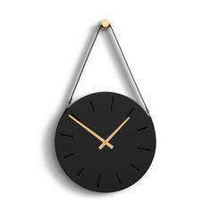 a black and gold clock hanging from the wall with two hands on each side of it