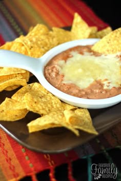 a plate with tortilla chips and a bowl of refried beans on it