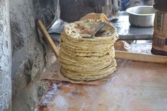 a stack of tortilla sitting on top of a wooden table next to a knife