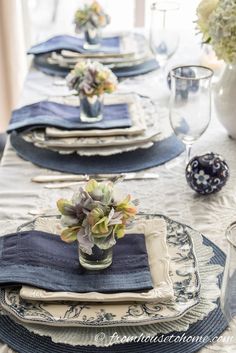 the table is set with blue and white place mats, silverware, and succulents