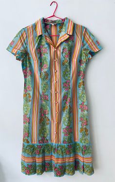 "This is such a cute vintage 80's short sleeved shirt dress with stripes and a lovely flower patterned panels in bright vivid colours of pink, yellow, orange and turquoise, the dress is made from a polyester fabric, it has baby pink buttons on the front and ruffle skirt. The dress is in excellent vintage condition. All garments are worn but in a good vintage condition, there may be small signs of wear or very minor flaws that are due to come with the items age but any more serious flaws that we find have been pictured. We do not except any returns for any sizing issues since we provide measurements, make sure to check them carefully and please ask for any extra information you might need that not be provided already, we measure our garment flat from side to side, armpit to armpit, hip to h Fitted Multicolor Short Sleeve Shirt Dress, Multicolor Cotton Dresses With Buttons, Pink Floral Print Short Sleeve Shirt Dress, Multicolor Buttoned Shirt Dress For Summer, Colorful Short Sleeve Dress With Vibrant Print, Colorful Vibrant Print Short Sleeve Dress, Colorful Vibrant Short Sleeve Dress, Vibrant Colorful Short Sleeve Dresses, Retro Short Sleeve Dress With Buttons