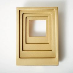 three square shaped gold metal objects on a white surface