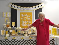 an older woman standing in front of a table with cakes and cupcakes on it