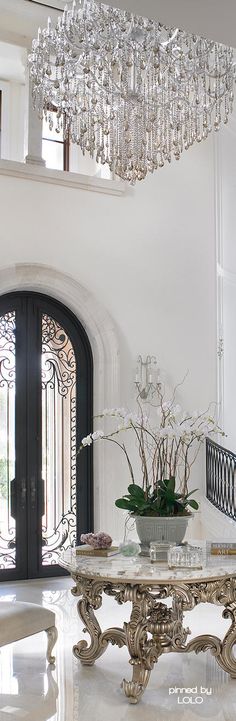 an elegant foyer with chandelier and marble table in front of the staircase leading up to the second floor