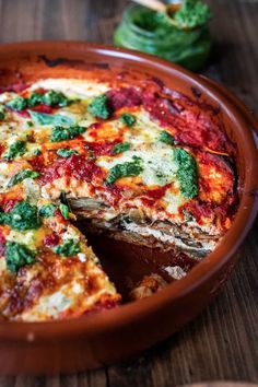 a pizza pie with spinach and cheese in a brown dish on a wooden table