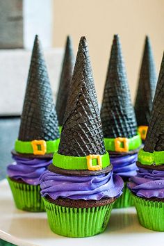 some cupcakes with witches hats on them are sitting on a white cake plate