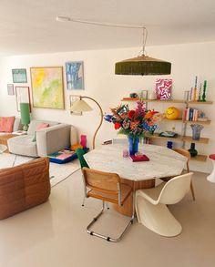 a living room filled with lots of furniture and flowers on top of a white table