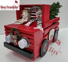 a red truck with two stuffed animals in it's back and christmas decorations on the front