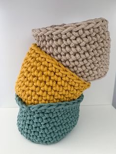 three crocheted baskets stacked on top of each other in different colors and sizes