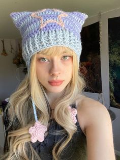 a woman with long blonde hair wearing a knitted hat and posing for the camera