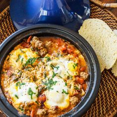 an image of a bowl of food with bread on the side