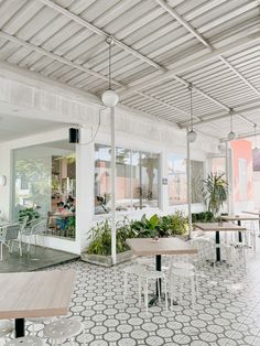 the inside of a restaurant with tables, chairs and potted plants on the floor