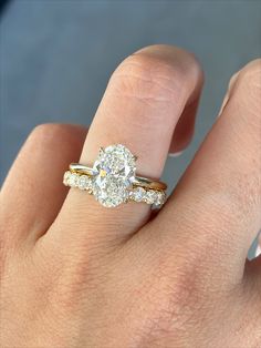 a woman's hand with a diamond ring on top of her finger and the engagement band