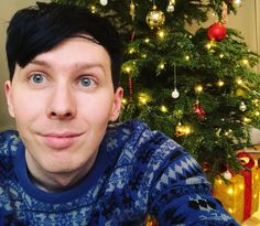 a man is taking a selfie in front of a christmas tree