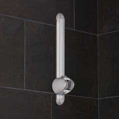 a close up of a shower handle on a tiled wall in a bathroom with black tiles