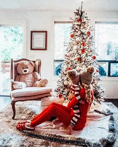 a christmas tree with red and white striped stockings on it next to a teddy bear