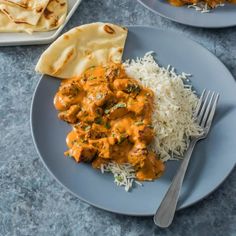 two plates filled with rice and chicken curry next to naan bread on a table