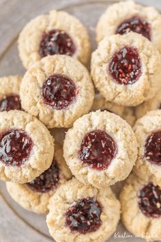 small cookies with jam on them sitting on a glass plate, ready to be eaten