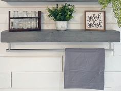 a shelf with some plants on top of it next to a towel and potted plant