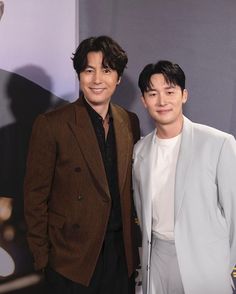 two men standing next to each other on a red carpet