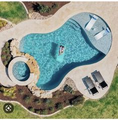 an aerial view of a swimming pool surrounded by lawn chairs and lounges, with two people in the water