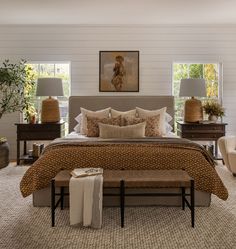 a large bed sitting in a bedroom next to two chairs and a table with lamps on it